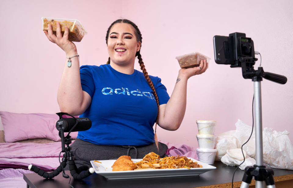 Vlogger Charna Rowley, 22, from London, in her bedroom making an eating YouTube video. [Photo: Caters]