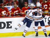 Edmonton Oilers winger Zach Hyman, left, celebrates his goal against the Calgary Flames with Darnell Nurse as Flames on the bench watch during the third period of Game 2 of an NHL hockey Stanley Cup playoffs second-round series Friday, May 20, 2022, in Calgary, Alberta. (Jeff McIntosh/The Canadian Press via AP)