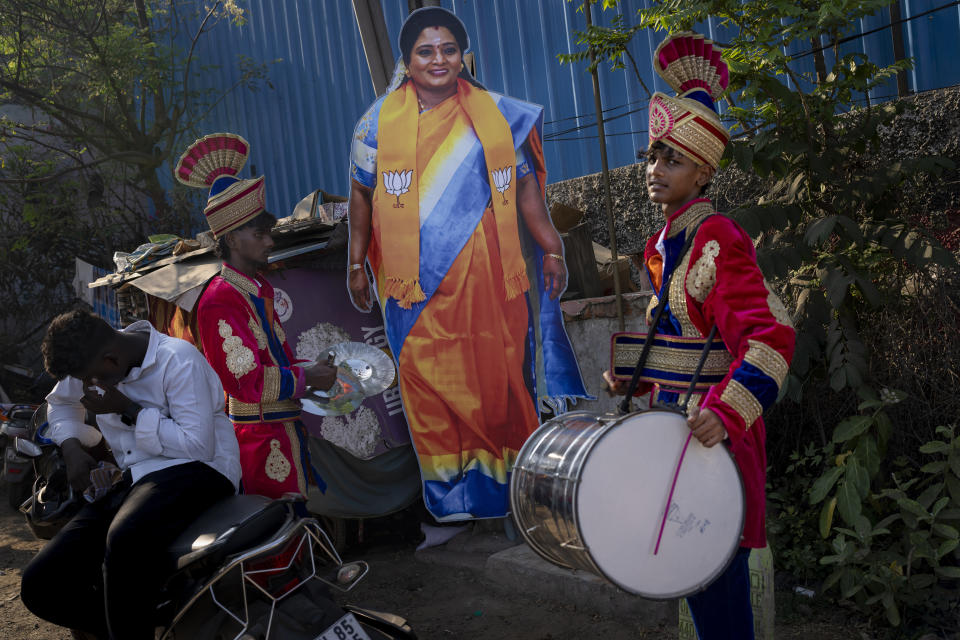Members of a local band wait next to a large cutout portrait of Bharatiya Janata Party (BJP) candidate Tamilisai Soundararajan as they wait for her arrival for an election campaign rally ahead of country's general elections, in the southern Indian city of Chennai, April 14, 2024. (AP Photo/Altaf Qadri)