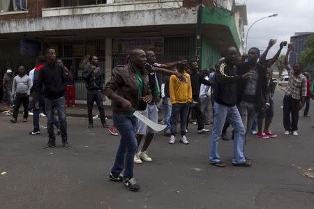 A group of foreign nationals threaten to defend themselves as police get between them and South Africans after a peace march in Durban, South Africa, April 16, 2015. REUTERS/Rogan Ward