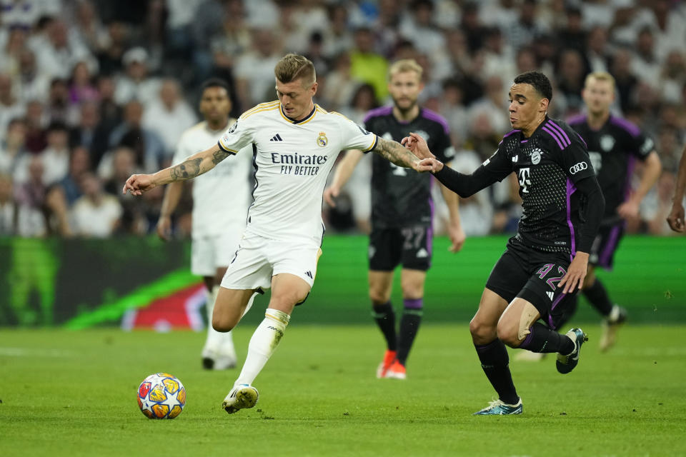 Real Madrid's Toni Kroos, left, challenges for the ball with Bayern's Jamal Musiala during the Champions League semifinal second leg soccer match between Real Madrid and Bayern Munich at the Santiago Bernabeu stadium in Madrid, Spain, Wednesday, May 8, 2024. (AP Photo/Jose Breton)