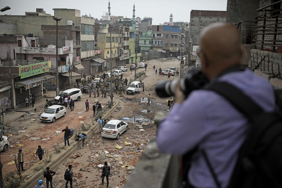 In this Thursday, Feb. 27, 2020 photo, a photojournalist takes photographs of Indian paramilitary soldiers patrolling a street vandalized in Tuesday's violence in New Delhi, India. Reporting in India has never been without its risks, but journalists say attacks on the press during last week's deadly communal riots between Hindus and Muslims in New Delhi show the situation is deteriorating. (AP Photo/Altaf Qadri)