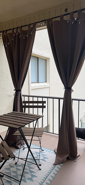 a reviewer photo of two of the curtains tied back on a balcony 