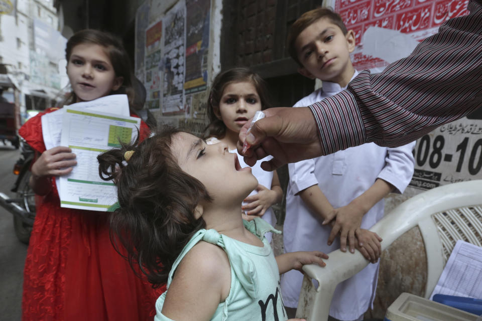 A health worker gives a polio vaccine to a child in a neighborhood of Lahore, Pakistan, Monday, May 23, 2022. Pakistan launched a new anti-polio drive on Monday, more than a week after officials detected the third case so far this year in the country's northwestern region bordering Afghanistan. (AP Photo/K.M. Chaudary)