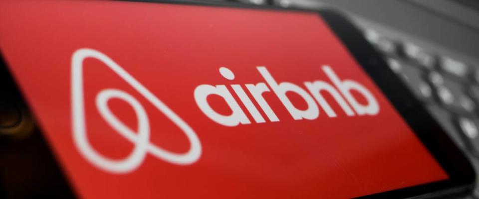 Close up of isolated mobile phone with red airbnb logo lettering on computer keyboard.