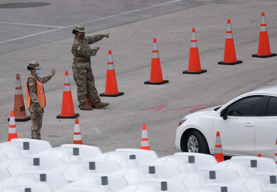 National Guard members direct cars, Wednesday, Aug. 5, 2020, at a COVID-19 testing site outside Hard Rock Stadium in Miami Gardens, Fla. State officials say Florida has surpassed 500,000 coronavirus cases. Meanwhile, testing is ramping up following a temporary shutdown of some sites because of Tropical Storm Isaias. (AP Photo/Wilfredo Lee)