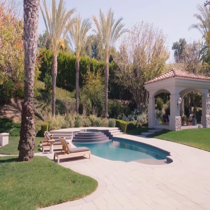 The backyard is a huge open space complete with an outdoor seating area and a pool surrounded by palm trees