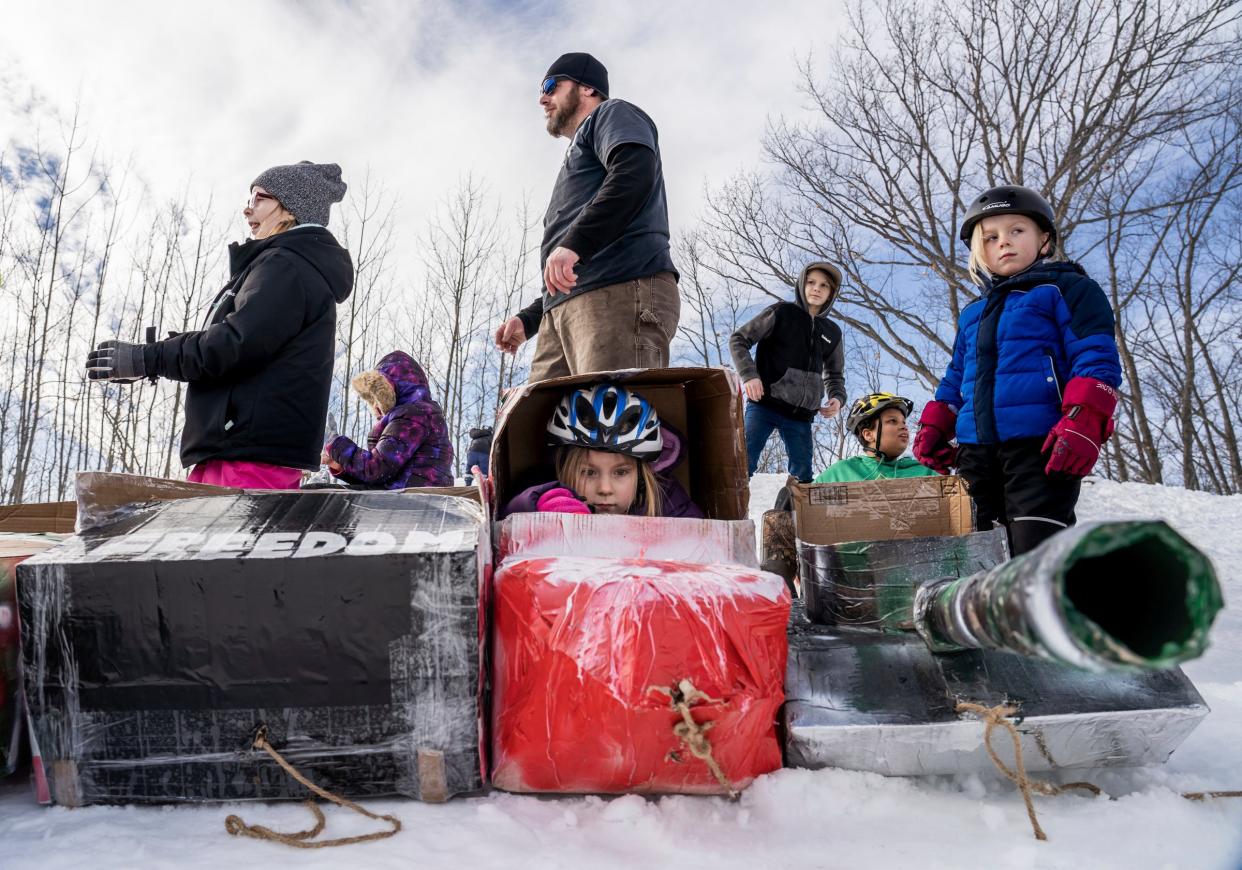 Isa Campbell, center, of Gwinn sits in her cardboard sled as her father Ambrose Campbell of Gwinn, sister Aryanna Campbell, left, and brother Ambrose Brody Campbell Jr., right, wait for the start of the K.I. Sawyer Cardboard Sled Races on Feb. 11, 2023.