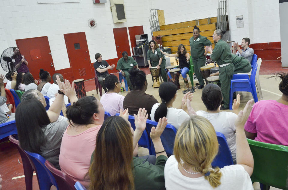 A crowd on inmates watching the performance begin to clap and chant along.