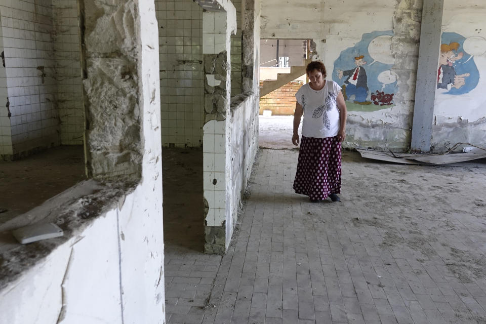 Devla Ajsic walks through the ruins of a former battery factory in Potocari near Srebrenica, Bosnia, Wednesday, July 7, 2021. Ajsic was 21 years old and three months pregnant in July 1995 when she was sexually assaulted in Srebrenica, eastern Bosnia, while her fiance and thousands of other men and boys were taken away and executed in Europe's only acknowledged genocide since World War II. (AP Photo/Eldar Emric)