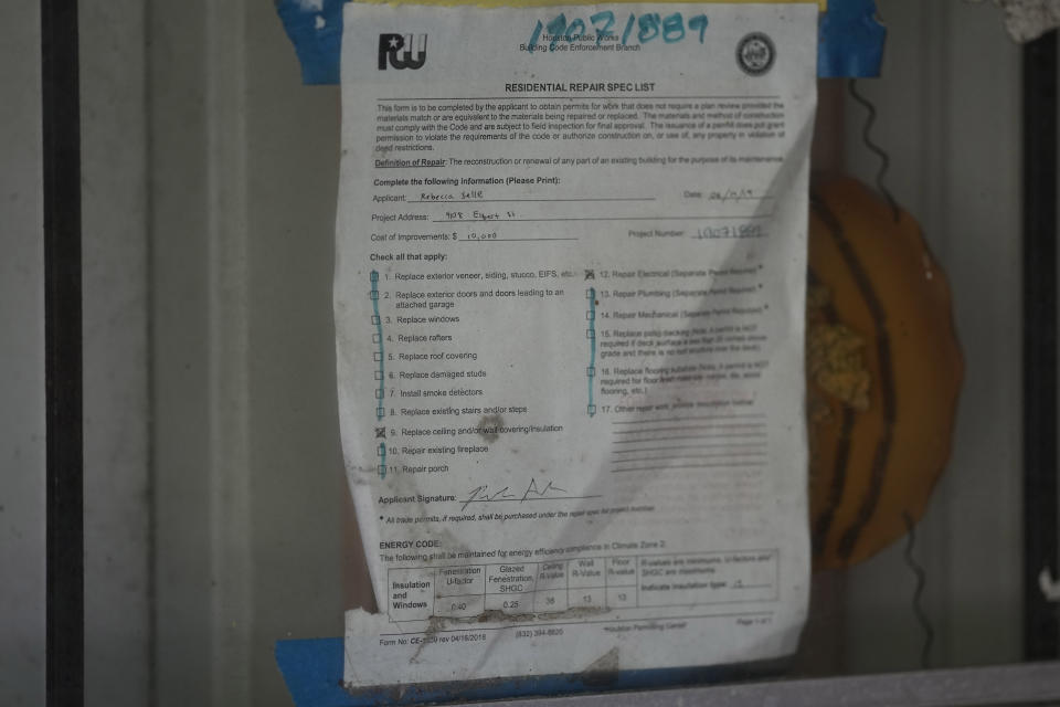 A weathered construction permit remains taped to the front door of Mal Moses's home, which was damaged by Hurricane Harvey in 2017, Thursday, Aug. 25, 2022, in Houston. A local nonprofit, West Street Recovery, ultimately helped repair his home. (AP Photo/David J. Phillip)