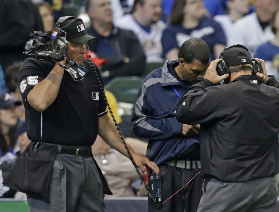 Umpire Ted Barrett (65) listens to a headset during instant replay in the sixth inning of an Opening day baseball game between the Atlanta Braves and Miwaukee Brewers Monday, March 31, 2014, in Milwaukee. Atlanta got a reversal of a call against the Milwaukee Brewers Ryan Braun at first base. (AP Photo/Jeffrey Phelps)