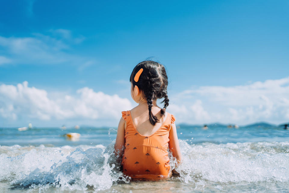 The back of a little girl sitting in the ocean