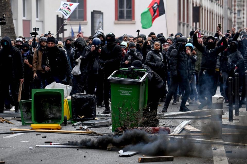 People stand behind makeshift barricades as they confront police (AFP via Getty Images)