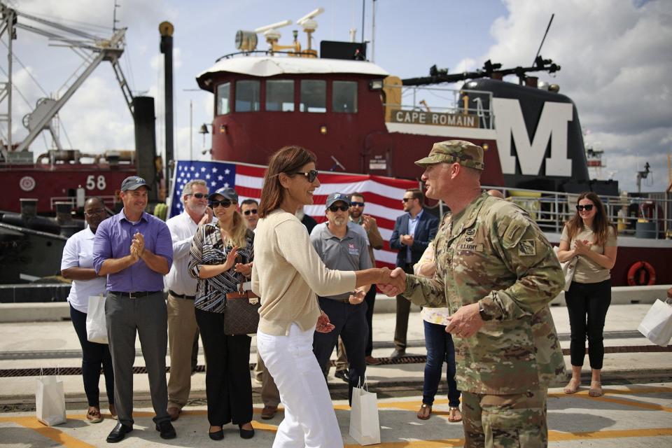U.S. Army Col. James Booth, commander of the Army Corps of Engineers district based in Jacksonville, hands out a commander's coin Monday to Barbara Nist, a geologist who helped on the river deepening project as they marked the end of the dredge at the Blount Island terminal.