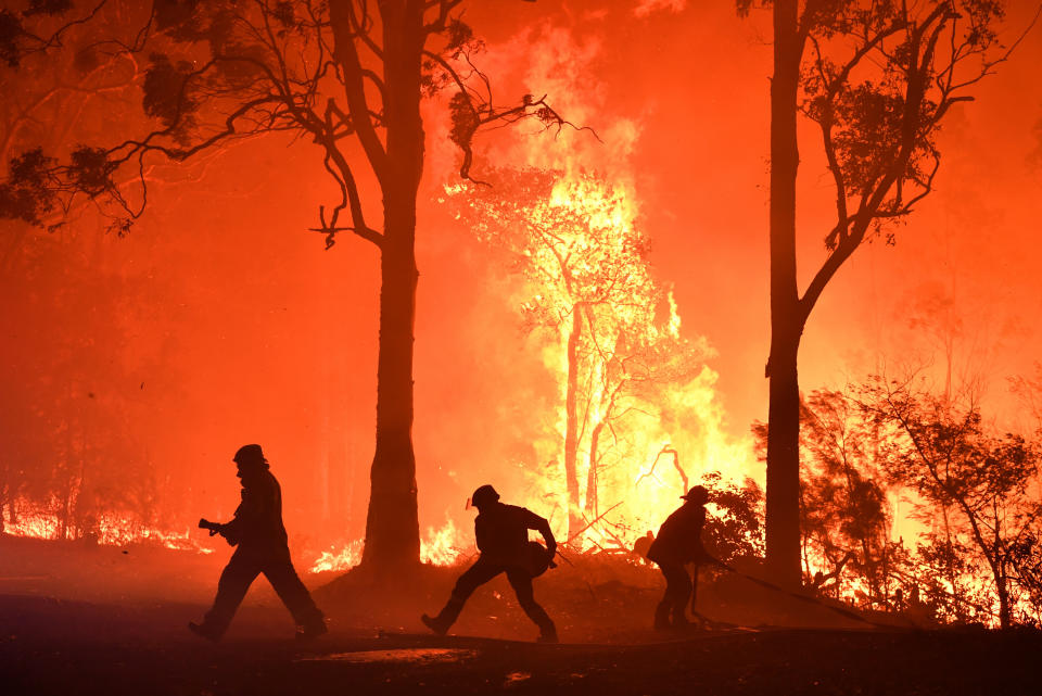 RFS volunteers and NSW Fire and Rescue officers fight a bushfire encroaching on properties near Termeil on the Princes Highway between Batemanâs Bay and Ulladulla south of Sydney,Tuesday, December, 3, 2019. (AAP Image/Dean Lewins) NO ARCHIVING