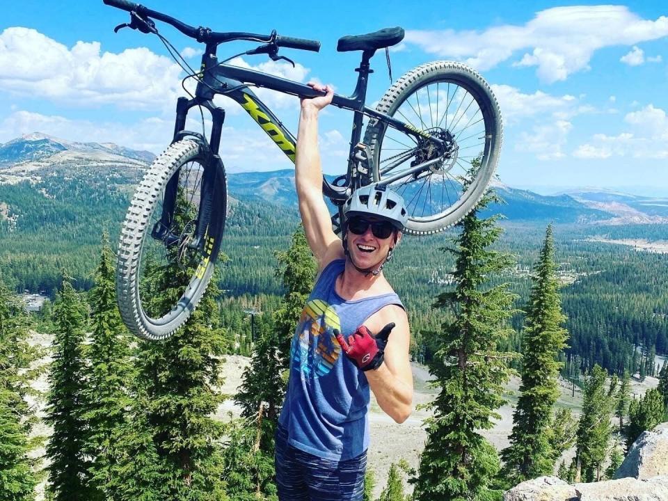 Colin Overweg holding up bike on top of mountain