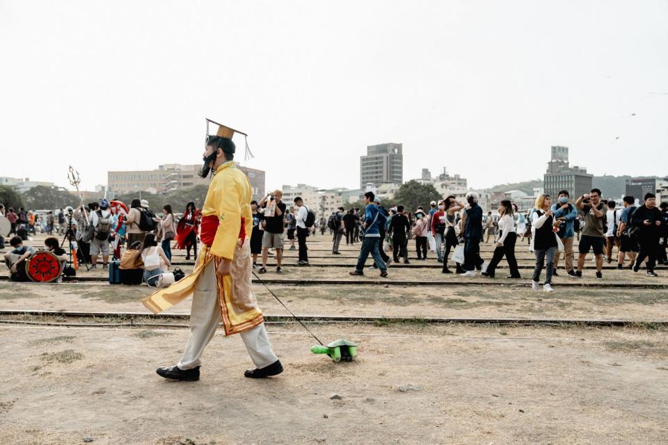 一名男子穿著皇帝服裝，一隻手遛著烏龜走在駁二園區，還原了近期最夯的話題《帝王條款》。（翻攝自駁二藝術特區 The Pier-2 Art Center臉書）