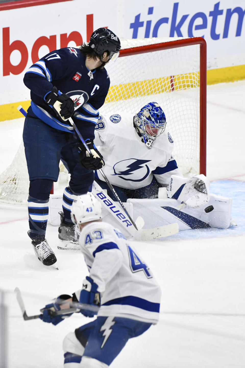Tampa Bay Lightning goaltender Andrei Vasilevskiy (88) makes a save on a Winnipeg Jets shot as Jets' Adam Lowry (17) looks for the rebound during the third period of an NHL hockey game Tuesday, Jan. 2, 2024, in Winnipeg, Manitoba. (Fred Greenslade/The Canadian Press via AP)