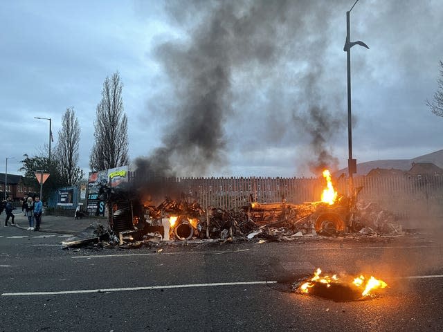 The wreckage of a Translink Metrobus on fire on the Shankill Road in Belfast