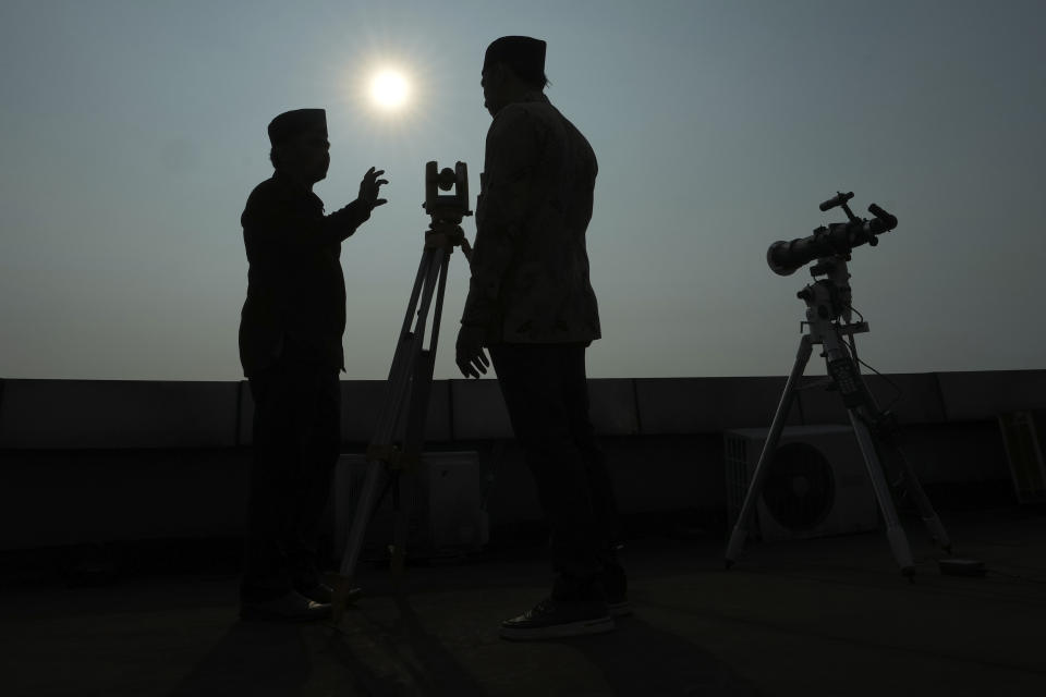 Officials are silhouetted as they use a telescope to scan the horizon for a crescent moon that will determine the beginning of the holy fasting month of Ramadan in Jakarta, Indonesia, Wednesday, March. 22, 2023. Millions of Muslims in Indonesia are gearing up to celebrate the holy month of Ramadan, which is expected to start on Thursday, with traditions and ceremonies across the world's most populous Muslim-majority country amid soaring food prices.(AP Photo/Achmad Ibrahim)