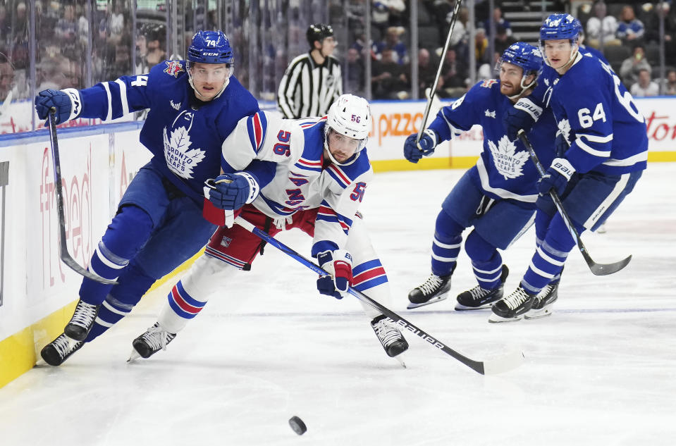 Toronto Maple Leafs forward Bobby McMann (74) and New York Rangers defenseman Erik Gustafsson (56) race for the puck during the second period of an NHL hockey game Tuesday, Dec. 19, 2023, in Toronto. (Nathan Denette/The Canadian Press via AP)