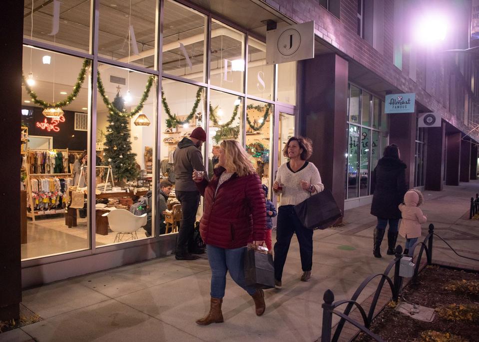 Shoppers walk through the Historic East Village during opening night of the Holiday Promenade on Friday, Nov. 19, 2021, in Des Moines.