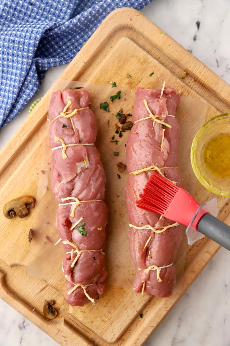 Starting with a long side, tightly roll up each tenderloin. Secure the seams with toothpicks. Then tie each tenderloin securely with kitchen string to hold it together.