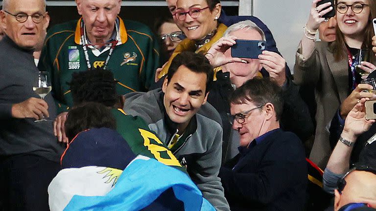 Roger Federer celebra con el capitán sudafricano Siya Kolisi en el Stade de France, detrás de un espectador envuelto en una bandera argentina; el ex tenista siguió la final del Mundial de Francia contra Nueva Zelanda como un hincha más de Springboks.