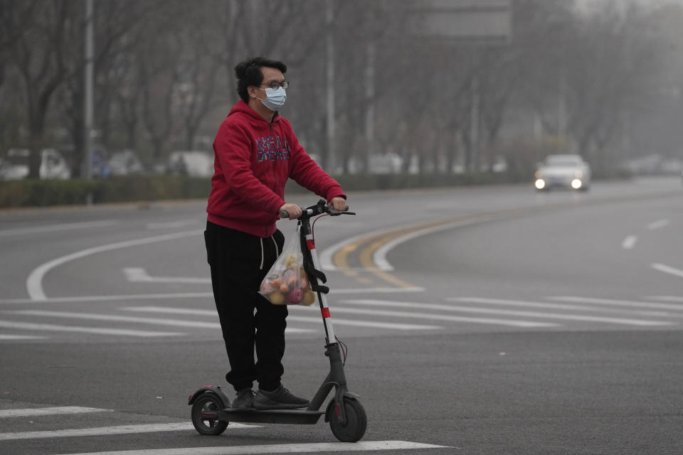 A resident rides a scooter along a quiet street in a district as restaurants are shut and residents encouraged to stay in their vicinity in Beijing, Thursday, Nov. 24, 2022. China is expanding lockdowns, including in a central city where factory workers clashed this week with police, as its number of COVID-19 cases hit a daily record. (AP Photo/Ng Han Guan)