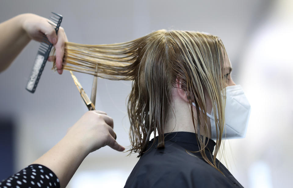 airdresser Jule Napiontek cuts the hair of her customer Sophie Pilgrim wearing a face mask in the 'Salon Success' in Magdeburg, Germany, Monday, March 1, 2021. Hairdressers across Germany have reopened for business this morning after a more than 2-month closure, another cautious step as the country balances a desire to loosen restrictions with concern about the impact of more contagious coronavirus variants. (Ronny Hartmann/dpa via AP)