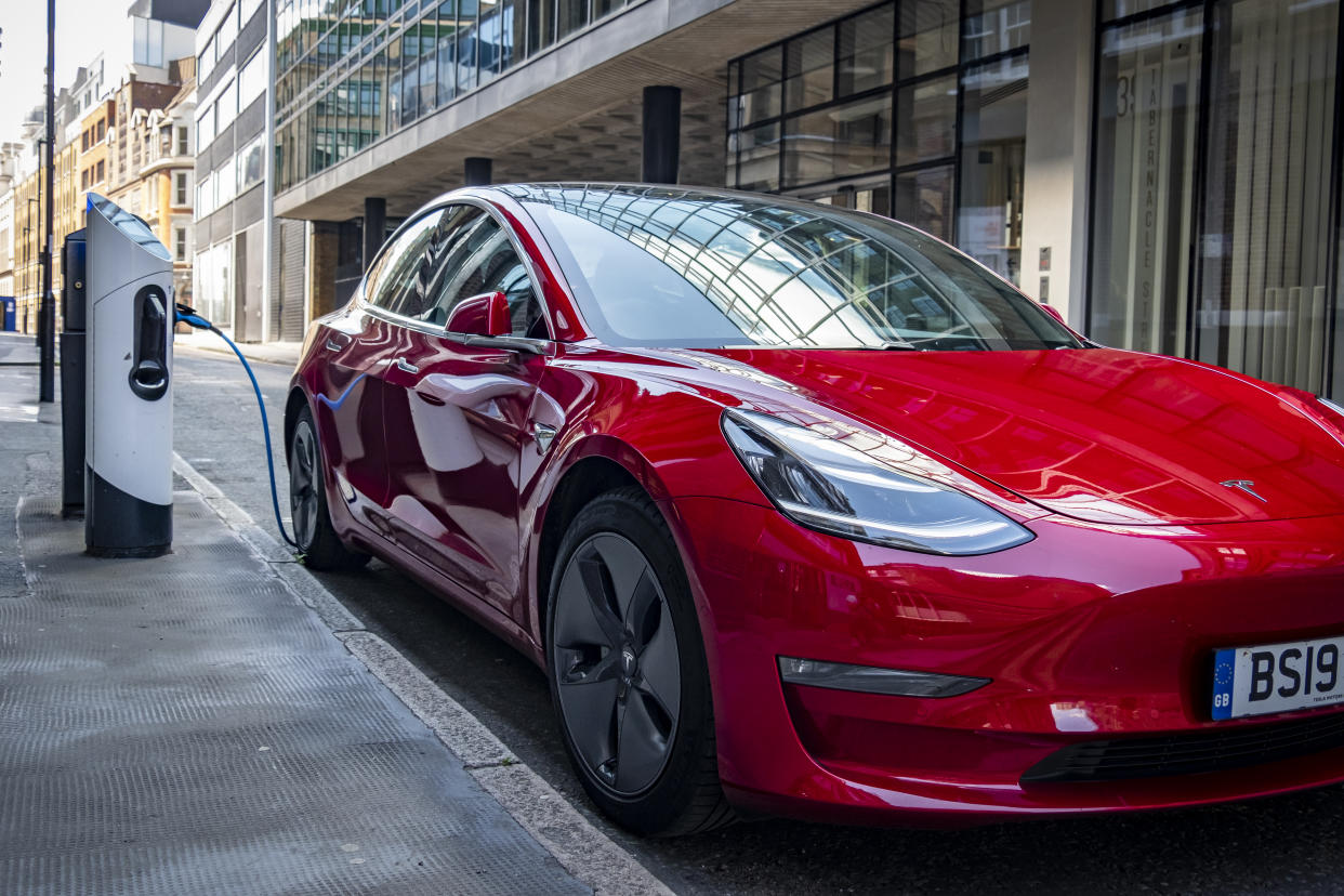 London, June 2020: A red Tesla Model 3 parked and charging in a designated charging bay in central London