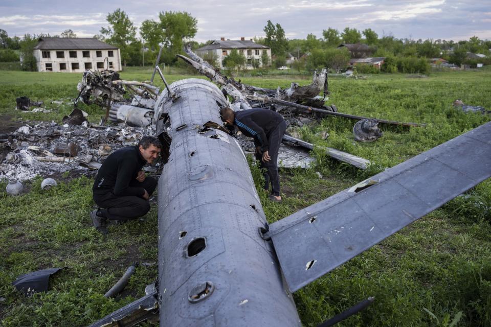 Residents check the remains of a destroyed Russian helicopter in the village of Malaya Rohan on Monday. (Bernat Armangue / AP)