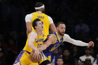 Los Angeles Lakers guard Austin Reaves (15) dribbles around a screen set by Los Angeles Lakers forward Anthony Davis and Golden State Warriors guard Stephen Curry, right, during the first half in Game 6 of an NBA basketball Western Conference semifinal series Friday, May 12, 2023, in Los Angeles. (AP Photo/Ashley Landis)