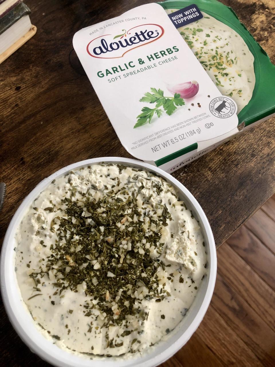 A bowl of garlic herb spreadable cheese topped with dried herbs