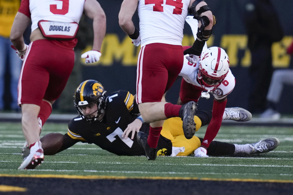 Iowa quarterback Spencer Petras (7) fumbles the ball as he is tackled by Nebraska defensive back Quinton Newsome (6) during the first half of an NCAA college football game, Friday, Nov. 25, 2022, in Iowa City, Iowa. (AP Photo/Charlie Neibergall)