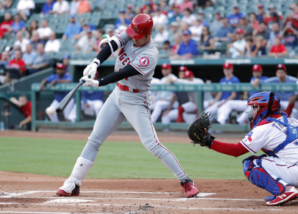 Los Angeles Angels' Shohei Ohtani swings at a pitch from Texas Rangers starter Brock Burke as catcher Jose Trevino watches in the first inning of a baseball game in Arlington, Texas, Tuesday, Aug. 20, 2019. Ohtani grounded out to shortstop Elvis Andrus in the at-bat. (AP Photo/Tony Gutierrez)