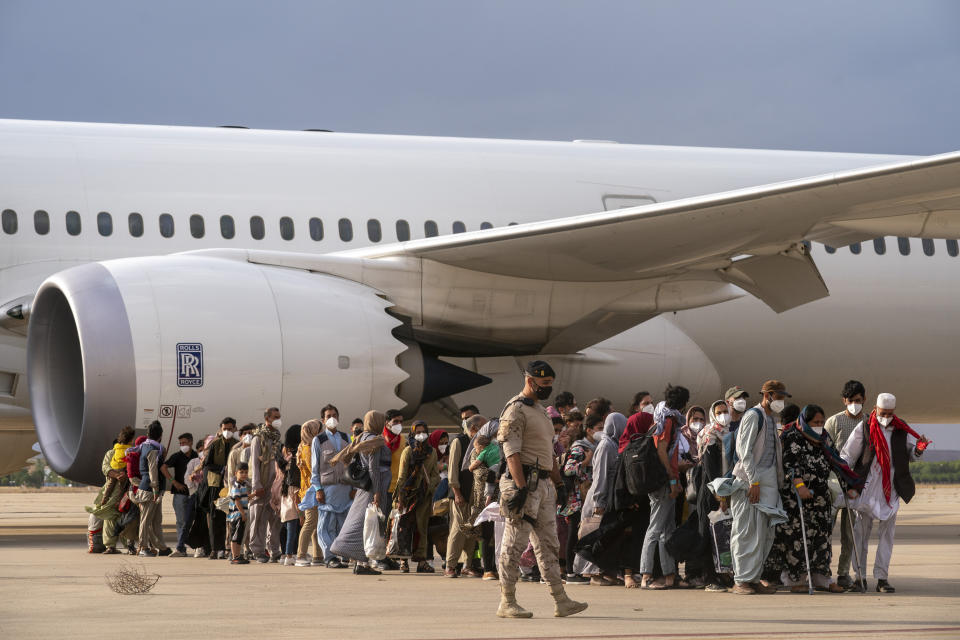 Afghan people who were transported from Afghanistan, walk after disembarking a plane, at the Torrejon military base as part of the evacuation process in Madrid, Monday. Aug. 23, 2021. (AP Photo/Andrea Comas)