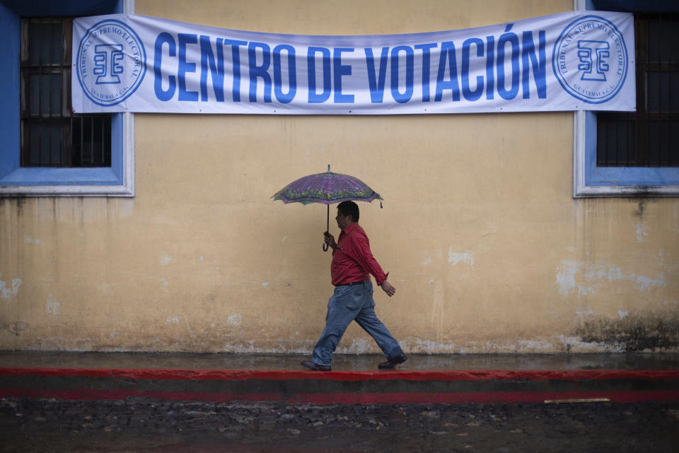 A man walks in the rain to a polling station during general elections in Antigua, Guatemala, Sunday, June 16, 2019. Voters are choosing between 19 candidates for a four-year presidential term that begins in Jan. 2020. The winner needs an absolute majority, making an August runoff between the two top vote-getters likely. (AP Photo/Santiago Billy)