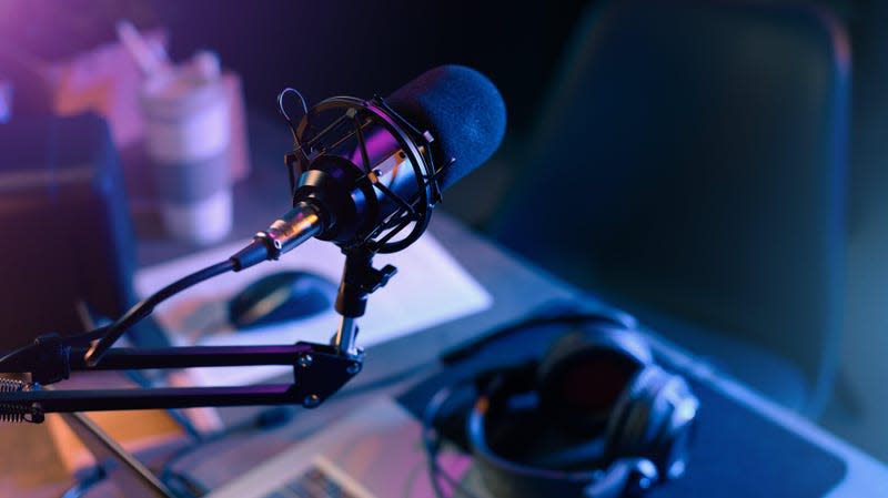 A professional microphone is shown above a computer and headphones.