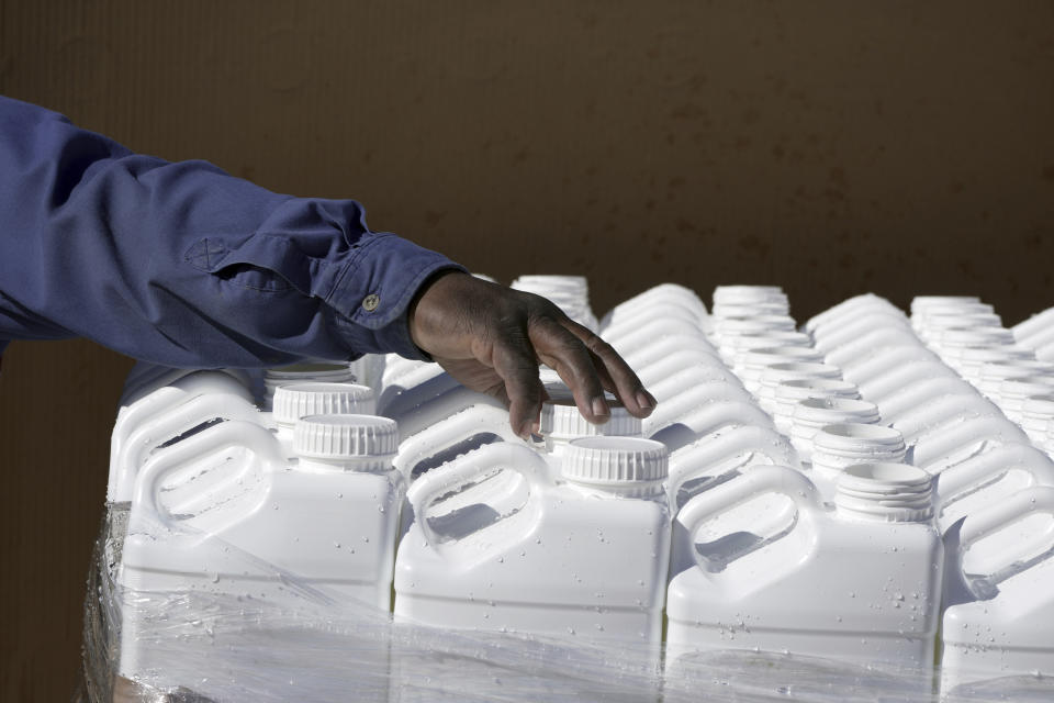 George Jackson fills up one gallon water jugs, while other Phillips County employees distribute water for people without water Tuesday, Jan. 30, 2024, in Helena, Arkansas. Parts of the east Arkansas town has been without water for two weeks after the state was hit by below freezing temperatures, and residents have been lining up for jugs of water and a truck of mobile showers dispatched to the community. (AP Photo/Karen Pulfer Focht)