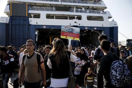 A travel agency employee holds a placard to gather refugees and migrants disembarking the Blue Star Patmos passenger ship at the port of Piraeus, near Athens, Greece, October 6, 2015. REUTERS/Alkis Konstantinidis