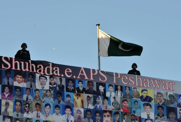 Pakistani police stand above photographs of students killed during a 2014 Taliban attack on a school during a ceremony in Peshawar, on November 16, 2015