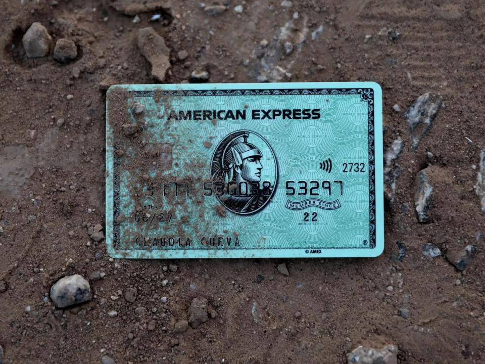 discarded American Express credit card in dirt