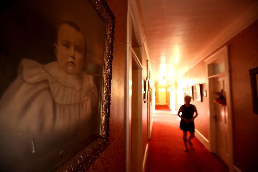 Terri LeDoux makes her way to her room past a series of framed vintage photos inside the historic Niles Hotel