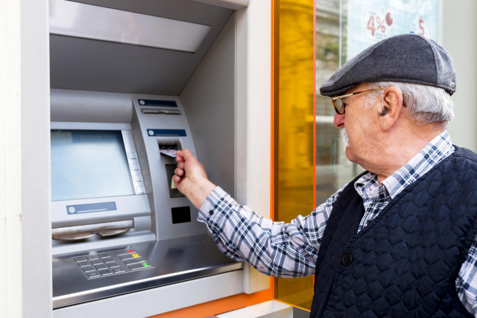 Senior man in hat inserting card into ATM