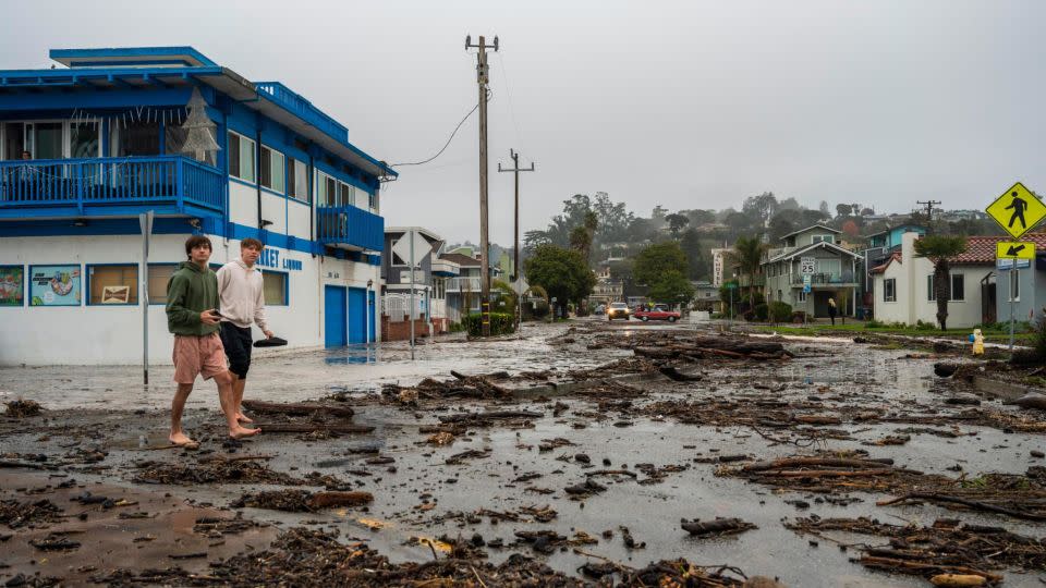Two men walk through ocean debris in the Rio Del Mar neighborhood of Aptos in Santa Cruz County. - Nic Coury/AP