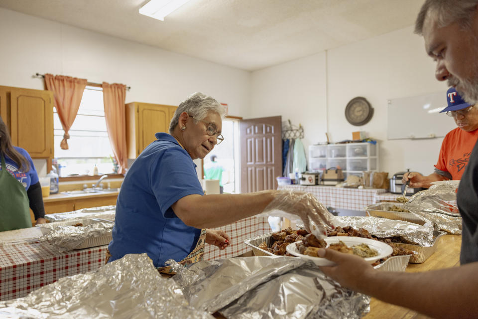 Ethel Humble, an elder at the Springfield United Methodist Church in Okemah, Okla., hands out a portion of the church's famous fried pork at their annual wild onion dinner, April 6, 2024. The church is on the Muscogee Nation's reservation, where the meals using wild onions picked by the community are an annual tradition. (AP Photo/Brittany Bendabout)