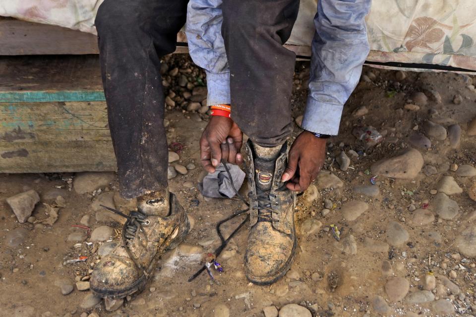 Aamir Shekh puts shoes on before going to work as a waste picker during a heat wave at a garbage dump on the outskirts of Jammu, India, Wednesday, June 19, 2024. Shekh and his family are among millions of people who scratch out a living searching through India's waste — and climate change is making a hazardous job more dangerous than ever. (AP Photo/Channi Anand)