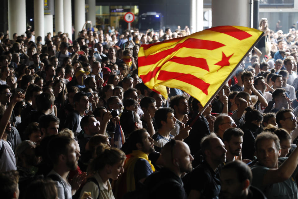 An Estelada pro-independence flag is waved among protestors at El Prat airport in Barcelona, Spain, Monday, Oct. 14, 2019. Spain's Supreme Court on Monday convicted 12 former Catalan politicians and activists for their roles in a secession bid in 2017, a ruling that immediately inflamed independence supporters in the wealthy northeastern region. (AP Photo/Emilio Morenatti)